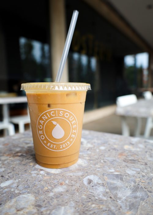Iced latte with Organic Squeeze logo sitting on a countertop